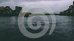 Rain drops on the water surface, waves, mountains and hills blur nature background, moss in Iceland Two snorkeling people on the b