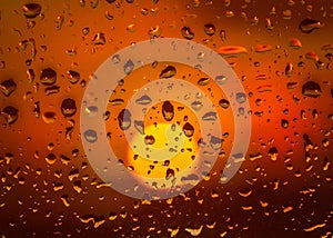 Rain drops on a window during a beautiful golden sunset. The sun is round soft focused the refelction of the sun can be seen