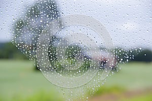 Rain drops on the window and blurry rural landscape