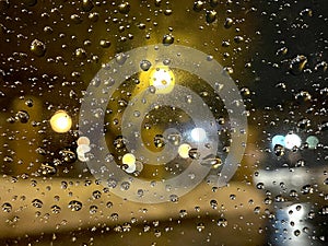 Rain drops on window with dark street bokeh lights.