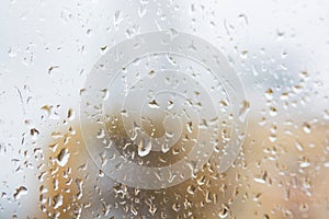 Rain drops on window glass surface with modern appartment building in background