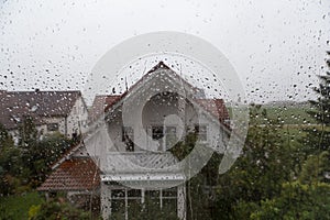 Rain drops on window glass with view to the neighbor house