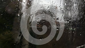 Rain Drops on the window of a moving train in spring with trees, bushes and houses passing by