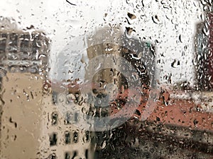 Rain drops on window pane against buildings in a rainy day