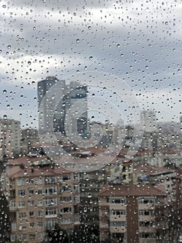 Rain drops on window pane against city view