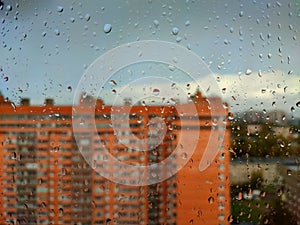 rain drops on a window pane against city view in a rainy day