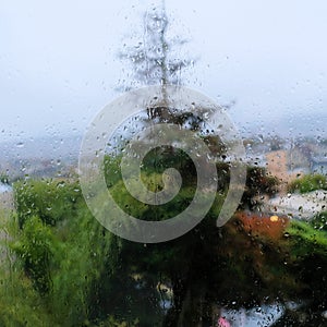 Rain drops on a window pane with blurred tree in background