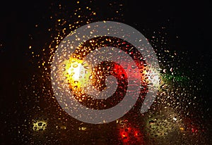 Rain drops on window with road light bokeh,water drop on the glass, night storm raining car driving concept. night car