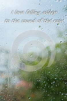 Rain drops on window with text `I love falling asleep to the sound of rain`