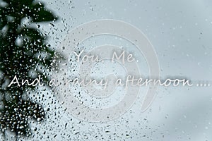 Rain drops on window and text `You.Me. And a rainy afternoon` Tender amorous concept in bad weather days