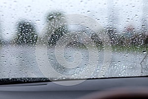 Rain drops on the windshield with the road.