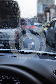 Rain drops on the windshield seeing from an interior of a car during a traffic jam.