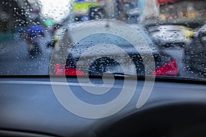 Rain drops on the windshield seeing from an interior of a car during a traffic jam.