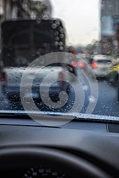 Rain drops on the windshield seeing from an interior of a car during a traffic jam.