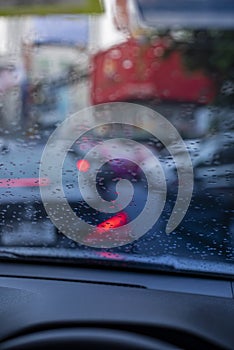 Rain drops on the windshield seeing from an interior of a car during a traffic jam.