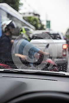 Rain drops on the windshield seeing from an interior of a car during a traffic jam.