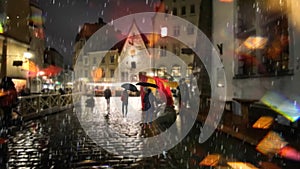 rain evening rainy street people walk with umbreellas city blurred light wet pavement medieval houses in Tallinn old town