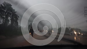 Rain falling on car windshield view. Drive car on road at heavy rain storm, inside a car driving,blurred traffic light background