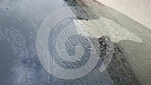 Rain glass car. Drops of close-up flow down the windshield of a standing car