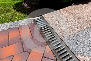 Rain grate to the joints of two paths of granite and paving slabs.