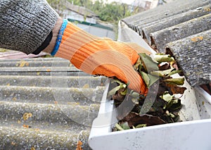 Rain Gutter Cleaning from Leaves in Autumn with hand. Gutter Cleaning. Roof Gutter Cleaning Tips.
