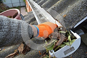 Rain Gutter Cleaning from leaves in autumn with hand. Roof gutter cleaning Gutter Cleaning photo