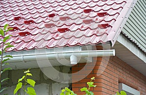 Rain gutter downspout drain pipe installation with metal roof snow board protection