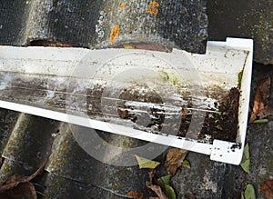 A rain gutter that has been blocked with dirt, debris and leaves is cleaned out to prevent damage to the roof and let the gutters