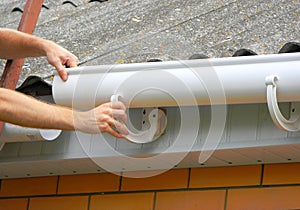 Rain gutter installation. Repair and renovate rain gutter pipeline on old house with asbestos rooftop