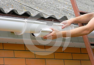 Rain gutter pipe renovation and repair on house asbestoc roof photo