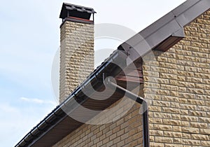 Rain gutter pipe system. Close up on Brick house with roof tiles and plastic roof gutter pipes drain on the corner. Guttering