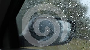 Rain outside the car window, view in the rearview mirror from a car at speed, driving in a car in the rain, weather