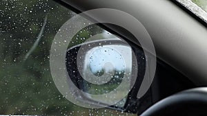 Rain outside the car window, view in the rearview mirror from a car at speed, driving in a car in the rain, weather