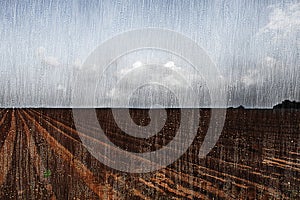 Rain on a plowed field. The photo effect of raindrops and torrential rain through a window pane