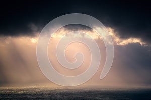 Rain on the sea with stormy clouds and sun rays