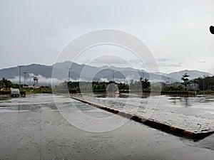 a rain soaked parking lot with mountains in the background and an umbrella