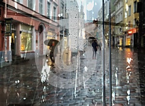 Rain in  town ,umbrella on asphalt on city street, ,modern building ,Rainy weather ,Autumn leaves on window frame ,wet drops ,nigh