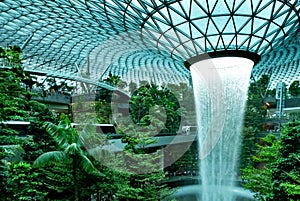 Rain Vortex, the world`s tallest indoor waterfall at Jewel Changi Airport. Green forest in the mall and skytrain. Iconic landmark