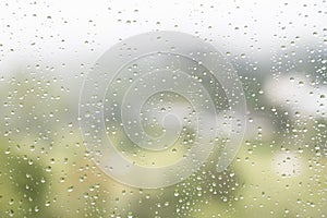 Rain water droplets on glass window with scenic greenery view