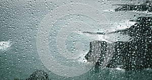 Rain water drops on window transparent glass abstract background. Gloomy ocean landscape with gray storm clouds. Fog