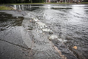 Rain water pushing up from under pavement sidewalk tarmac during flooding