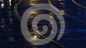 Rain wet road; lights; tram rails and colourful water reflections in the rain at dusk