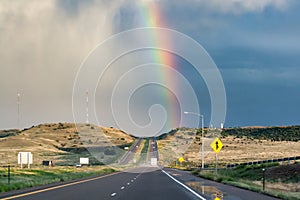 Rainbow above distant highway landscape after summer storm