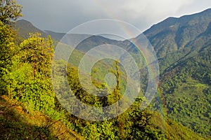 Rainbow above the green valley and mountain forest landscape