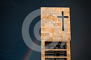 A rainbow above a modern church tower with christian cross