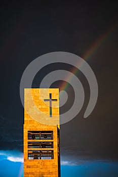 A rainbow above a modern church tower with christian cross