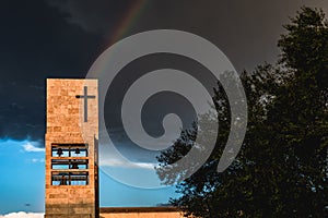 A rainbow above a modern church tower with christian cross