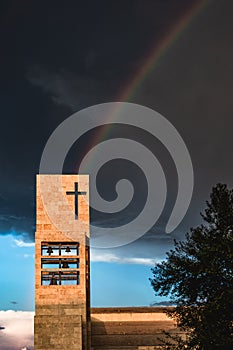 A rainbow above a modern church tower with christian cross