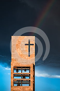 A rainbow above a modern church tower with christian cross