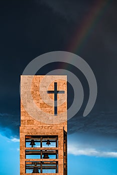 A rainbow above a modern church tower with christian cross